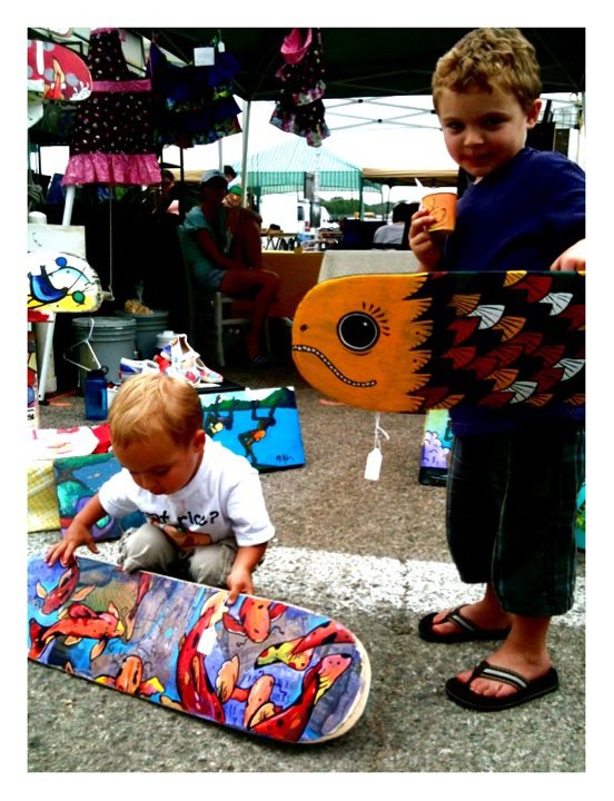 Cruz holding an original piece by Mike Johnston. Noah carrying an original piece by Lucas Aoki. Paint on repurposed skate boards.